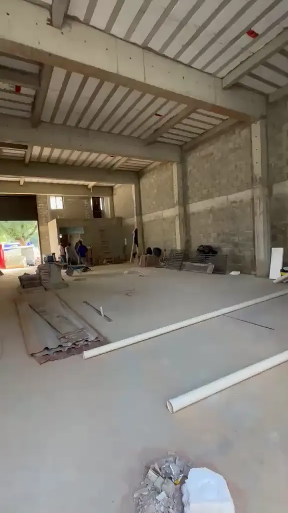 Panorama em vídeo da área interna de galpão comercial em obras em Jundiaí, exibindo a altura do pé-direito, lajes nervuradas pré-fabricadas e operários trabalhando ao fundo.