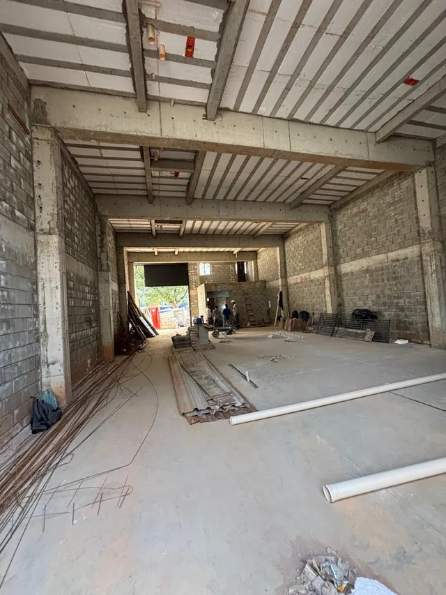 Vista interna de galpão industrial com pé-direito duplo em Jundiaí, mostrando estrutura de vigas de concreto pré-moldado, laje alveolar no teto, paredes em blocos de concreto e piso regularizado com tubulações.
