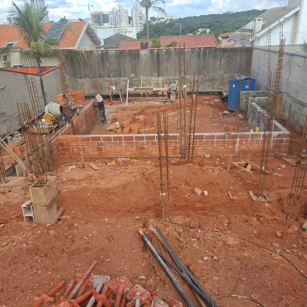 Paredes de tijolos em início de elevação, com pilares armados distribuídos pelo canteiro.