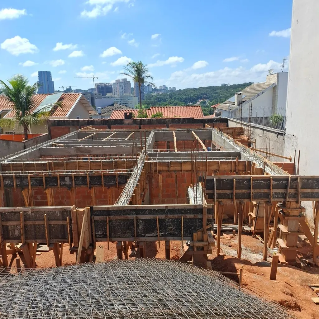 Estrutura com formas de madeira e armaduras de aço apoiadas sobre paredes já elevadas.